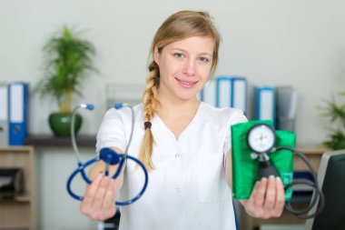 female doctor showing stethoscope and blood meassuring tool clipart