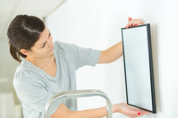 Vrouw Positionering Fotolijst Muur — Stockfoto