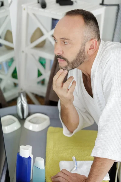 Homem Colocando Rosto Creme Olhando Espelho — Fotografia de Stock
