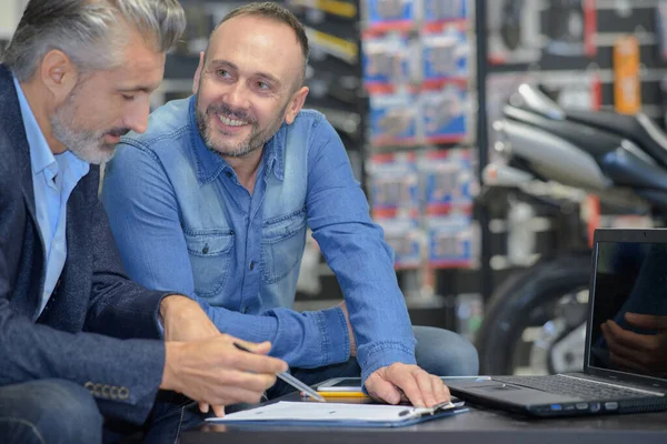 客户和推销员在摩托车展示室讨论交易 — 图库照片