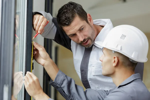 Vorgesetzter Beobachtet Lehrling Bei Markierung Der Position Fensterrahmen — Stockfoto