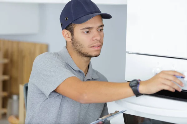 Genç Erkek Elektrikçi Mutfakta Fırın Tamir Ediyor — Stok fotoğraf