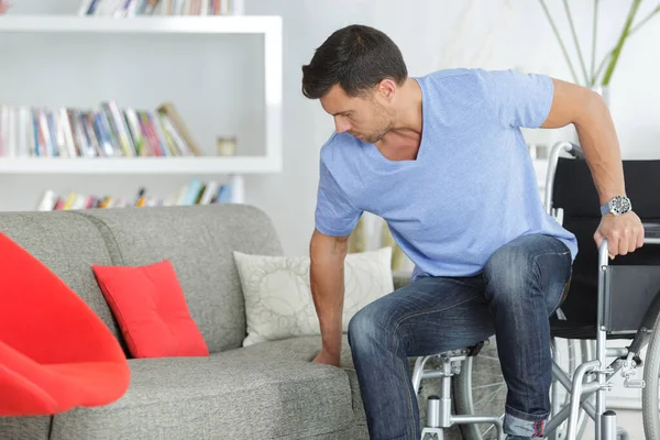 Deficiente Homem Movendo Sua Cadeira Rodas Para Sofá — Fotografia de Stock