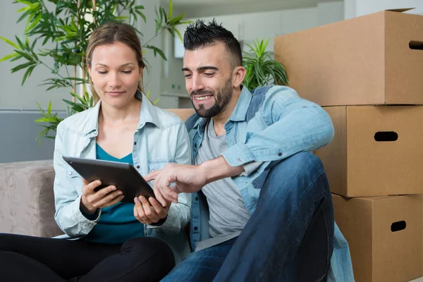 Coppia Guardando Tablet Tra Scatole Cartone — Foto Stock