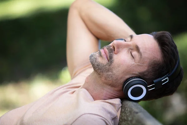 Muž Poslouchá Sluchátka Relaxaci Zpět Lavičce — Stock fotografie