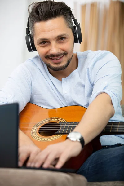 Uomo Sul Divano Che Suona Chitarra Con Computer Portatile Casa — Foto Stock