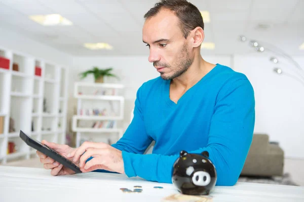 Man Met Behulp Van Een Spaarvarken Bank Met Rekenmachine — Stockfoto