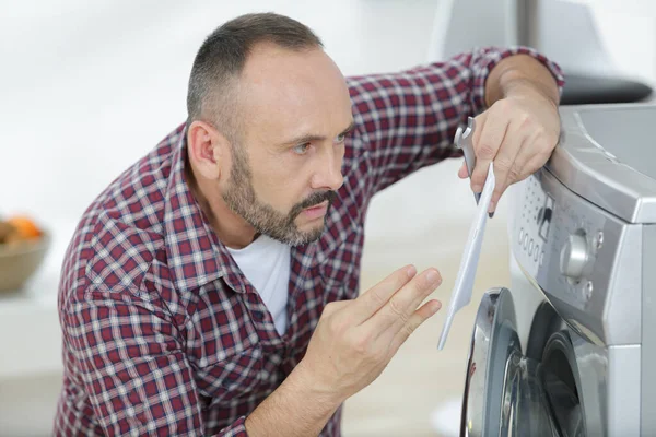 Adam Çamaşır Makinesine Bakıyor Talimatları Tutuyor — Stok fotoğraf