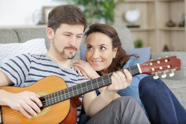 Frau Sieht Ihrem Partner Stolz Beim Gitarrespielen — Stockfoto