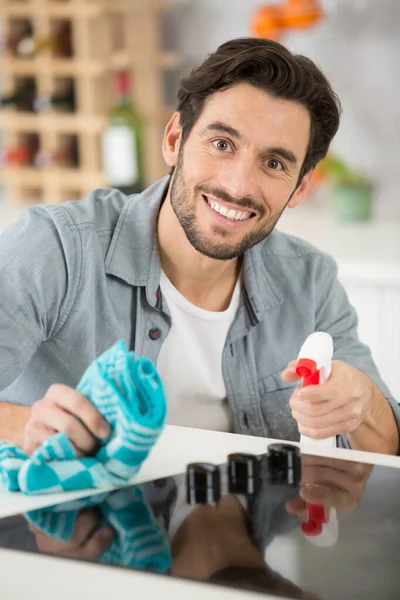 a man spraying detergent to clean the kitchen worktop