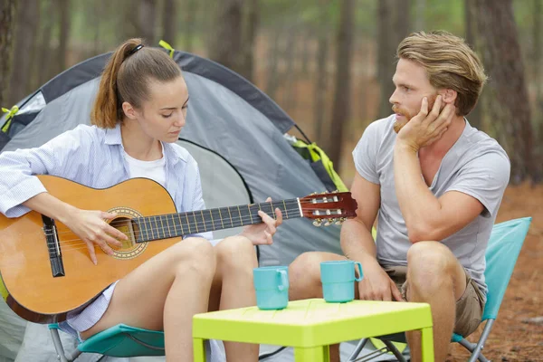 キャンプのカップルがギターを弾いていて — ストック写真