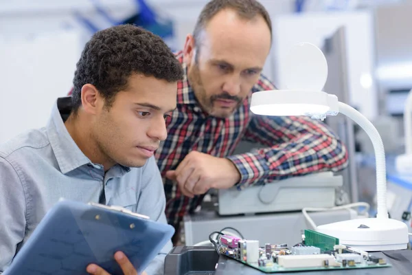 マイクロチップを観察する若い男性電気工学の学生は — ストック写真