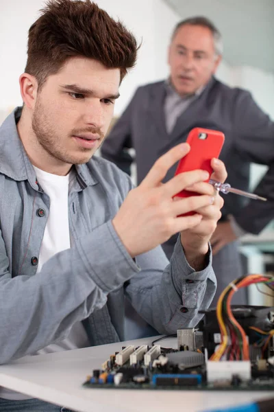 Zły Nauczyciel Elektryk Praktykant Patrząc Jego Smartfon — Zdjęcie stockowe