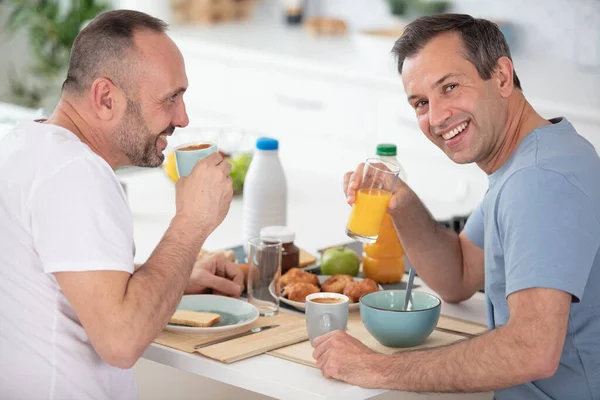ゲイのカップルは晴れた日にキッチンで朝食をとり — ストック写真