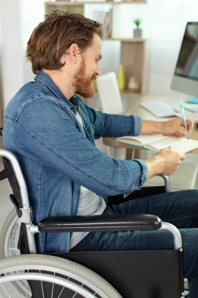 Человек Инвалидной Коляске Пишет Письменным Столом — стоковое фото