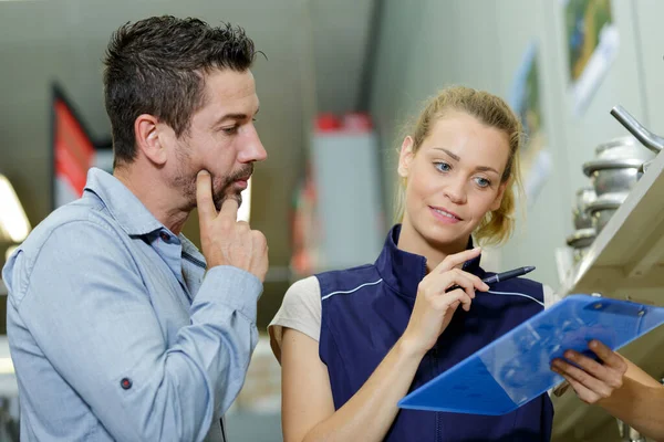 Verkäuferin Schaut Mit Kunde Auf Klemmbrett — Stockfoto