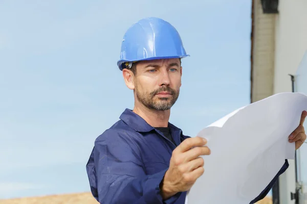 Manlig Byggnadsarbetare Som Håller Planer Utomhus — Stockfoto