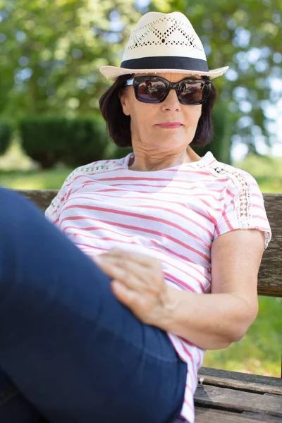 老太太笑着在公园的长椅上看书 — 图库照片