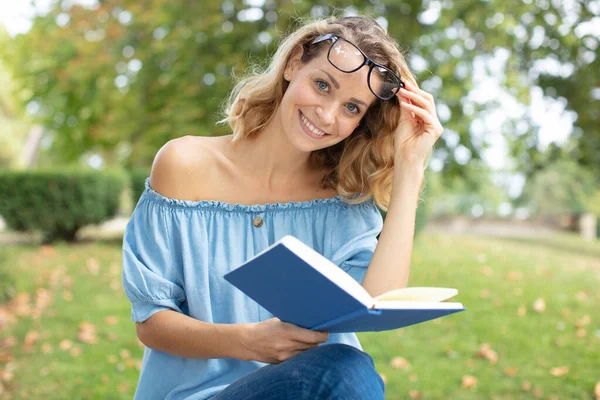 Mulher Sentou Grama Leitura Livro Levanta Seus Óculos — Fotografia de Stock