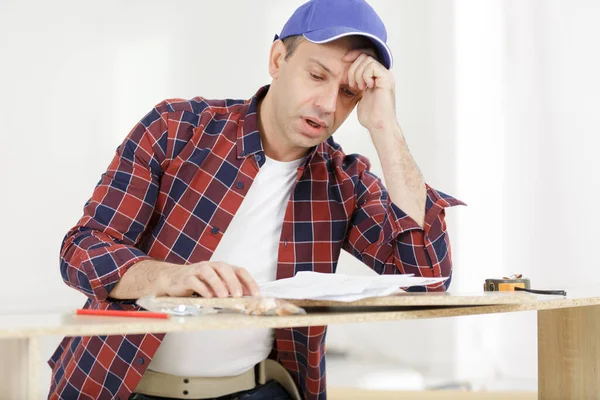 Frustrierter Mann Liest Anleitung Und Stellt Möbel Zur Selbstmontage Zusammen — Stockfoto