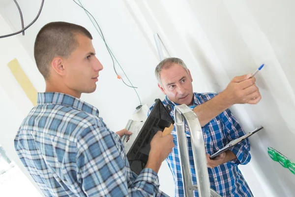 年轻的电工在新房子里安装插座 — 图库照片