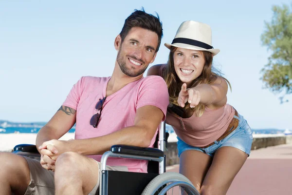 幸せな若いカップルが車椅子を指差して — ストック写真