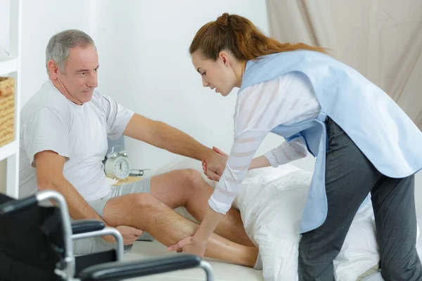 nurse practicing procedure to lift disabled patient from bed