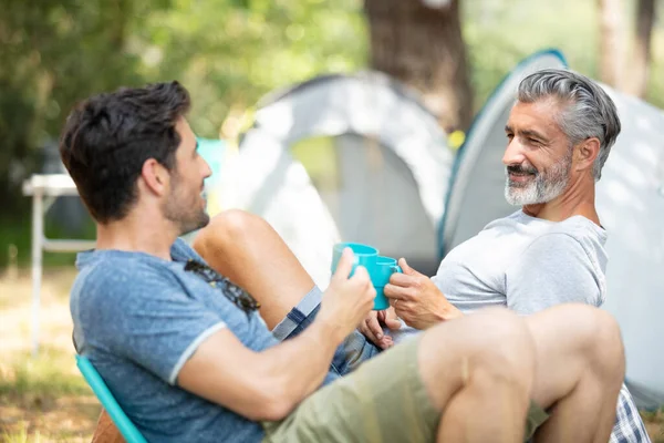 men on camping trip toasting with their plastic cups