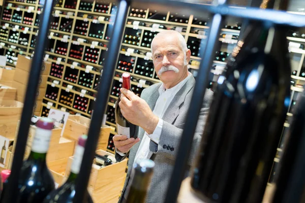 Ηλικιωμένος Άντρας Που Κρατάει Ένα Μπουκάλι Κρασί Στο Μαγαζί — Φωτογραφία Αρχείου