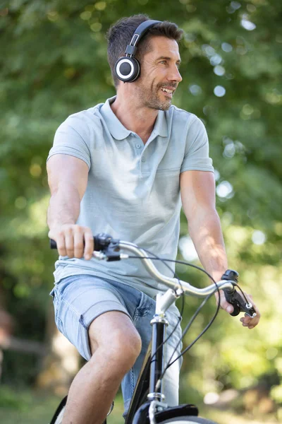 ヘッドフォンを装着した自転車に乗る大人の男性 — ストック写真