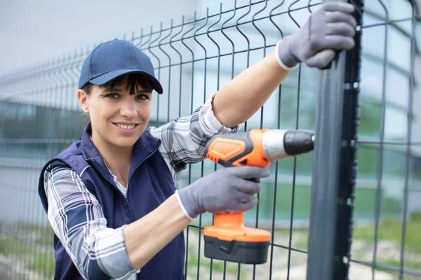 Travailleuse Avec Une Perceuse Contre Une Clôture Acier — Photo