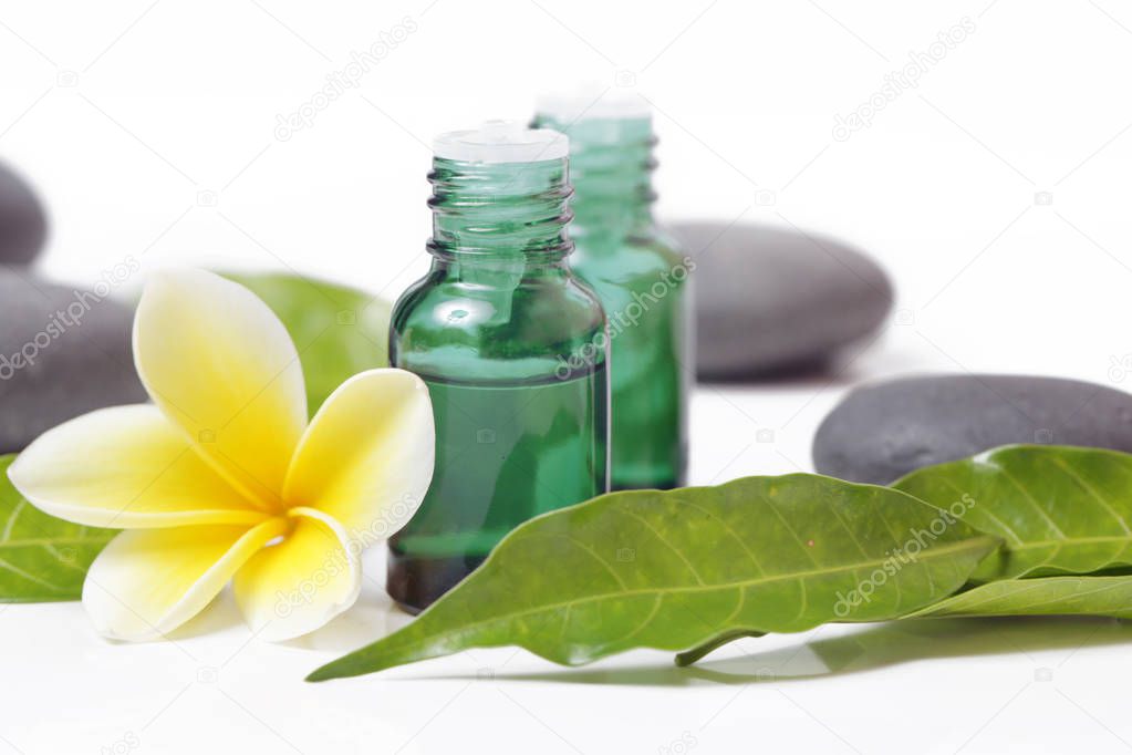 Green cosmetic bottles with zen stones and frangipani flower