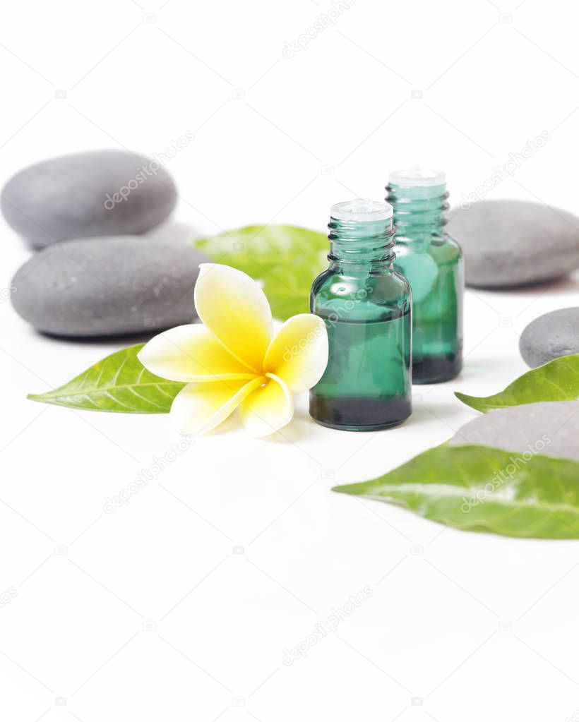 Green cosmetic bottles with zen stones and frangipani flower