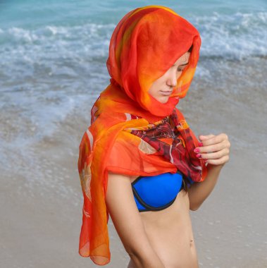 Sahilde turuncu eşarp genç kadınla