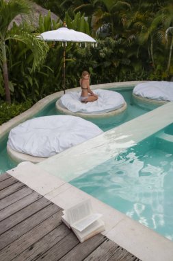 Genç kadın havuzun yanındaki rahatlatıcı