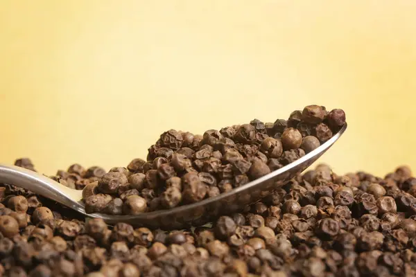Black Peppercorn Pada Latar Belakang Kuning — Stok Foto