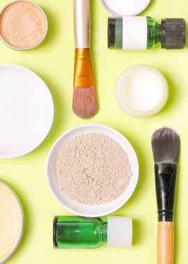 Sarı arka plan üzerinde farklı kozmetik ürünlerin üstten görünüm