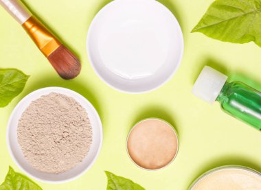 Sarı arka plan üzerinde farklı kozmetik ürünlerin üstten görünüm