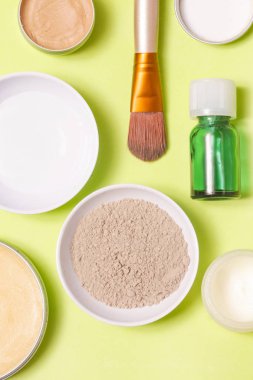 Sarı arka plan üzerinde farklı kozmetik ürünlerin üstten görünüm