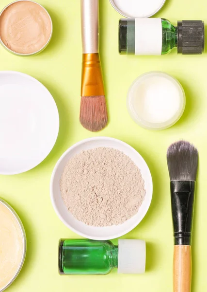 Sarı arka plan üzerinde farklı kozmetik ürünlerin üstten görünüm