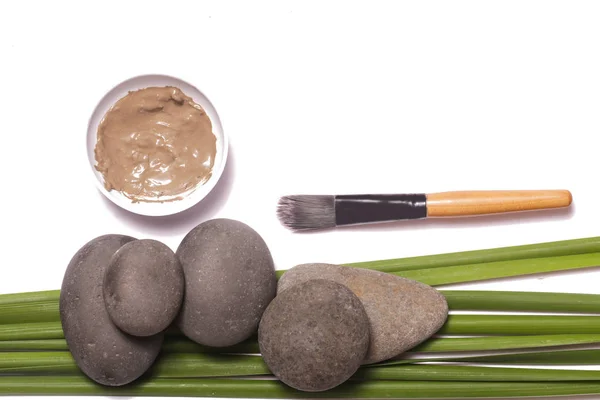White and green cosmetic clay beside zen stones, natural cosmetics products concept