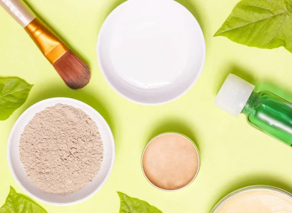 Sarı arka plan üzerinde farklı kozmetik ürünlerin üstten görünüm