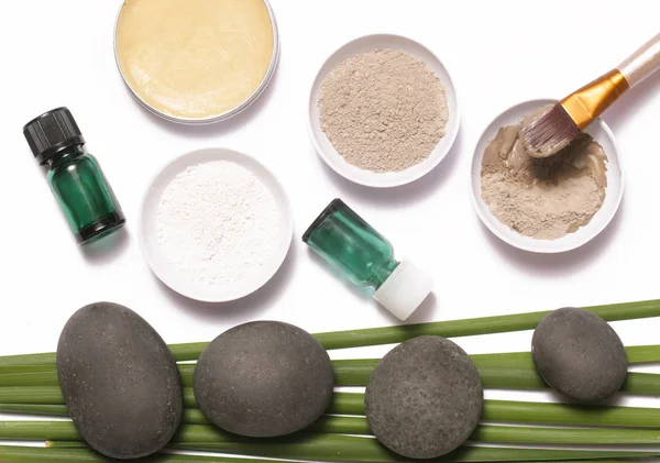 White and green cosmetic clay beside zen stones, natural cosmetics products concept