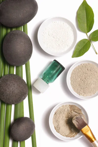 White and green cosmetic clay beside zen stones, natural cosmetics products concept