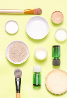 Sarı arka plan üzerinde farklı kozmetik ürünlerin üstten görünüm