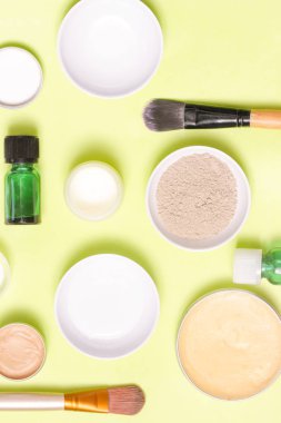 Sarı arka plan üzerinde farklı kozmetik ürünlerin üstten görünüm