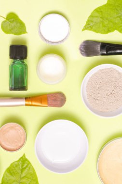 Sarı arka plan üzerinde farklı kozmetik ürünlerin üstten görünüm