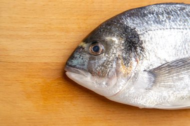 Yaldızlı kafalı çipura balık ahşap kesme tahtası üzerinde