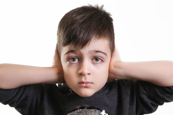 Студийный портрет мальчика, закрывающего уши - не слышно злого понятия
