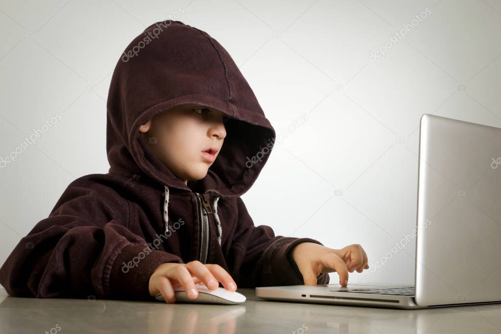 Young hacker in hoodie in front of laptop